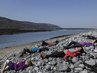 People lying onn the rocks relaxing beside the sea | Burren Guided Walks